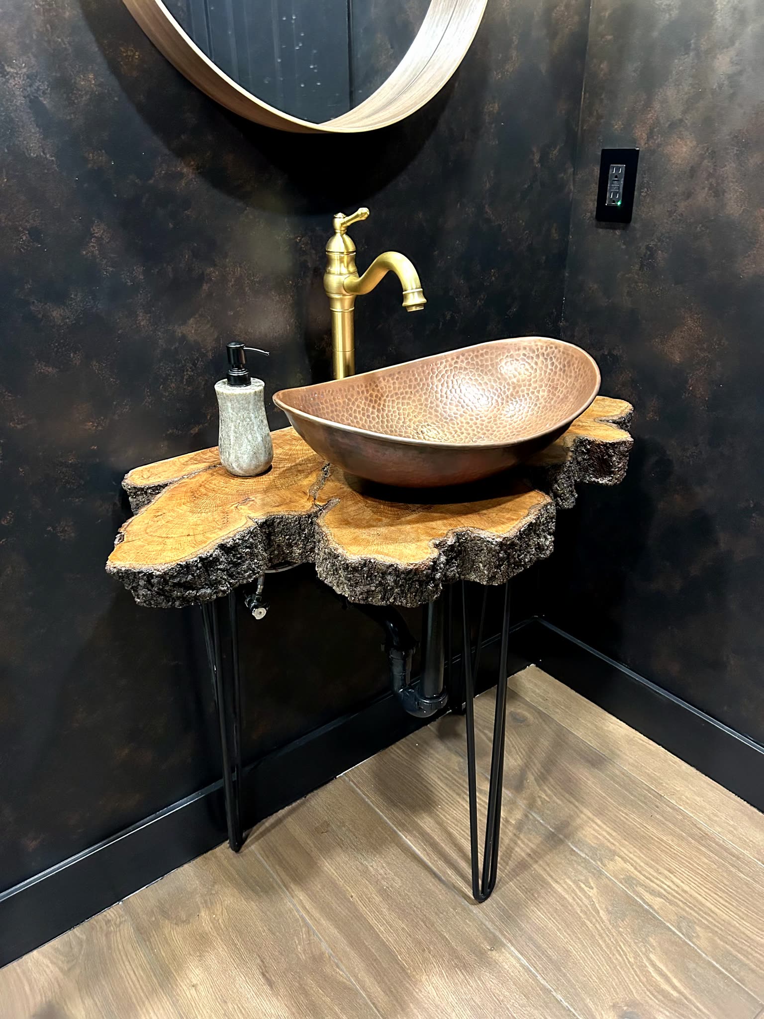 Live-edge live oak vanity top with hammered copper vessel sink in a moody black powder room